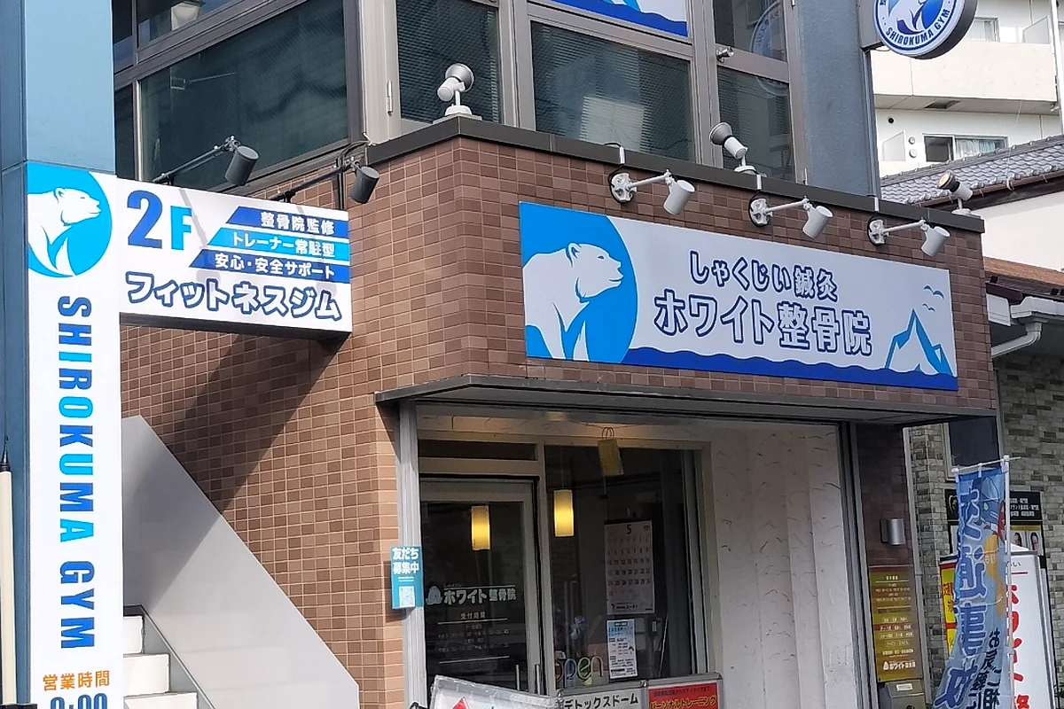 しゃくじいホワイト整骨院の外観。青いシロクマの看板が目印。2階は系列のSHIROKUMA GYM